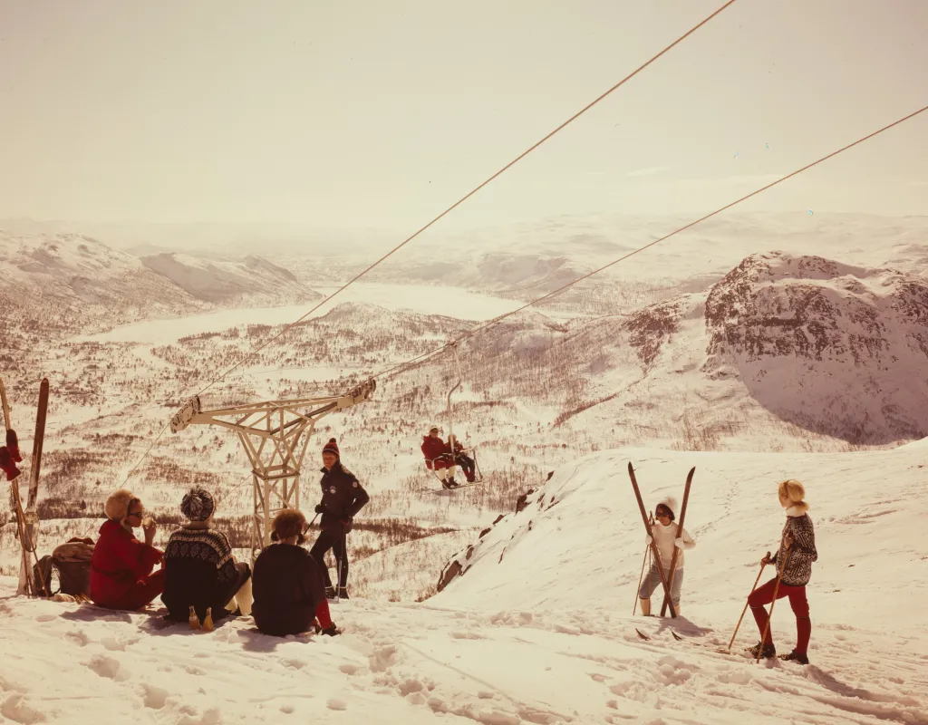 Gammelt foto fra 1969 som viser den første stolheisen, utsikt fra toppen av Storenos og skiturister i tidsriktig skiklær. Foto